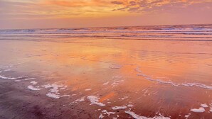 Une plage avec des vagues et un coucher de soleil.