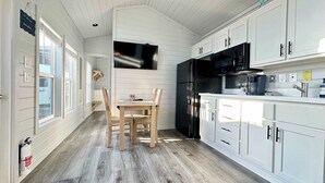 A kitchen with white cabinets, a black refrigerator, and a wooden dining table with chairs. - New Listing! Mins to Beach*2 Bdrm*Sleeps up to 6 (Bolivar Peninsula)