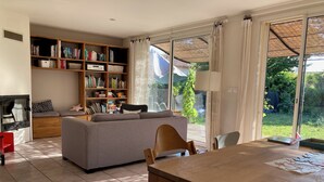 Un salón amplio con un sofá grande, una mesa de comedor de madera y una estantería llena de libros.