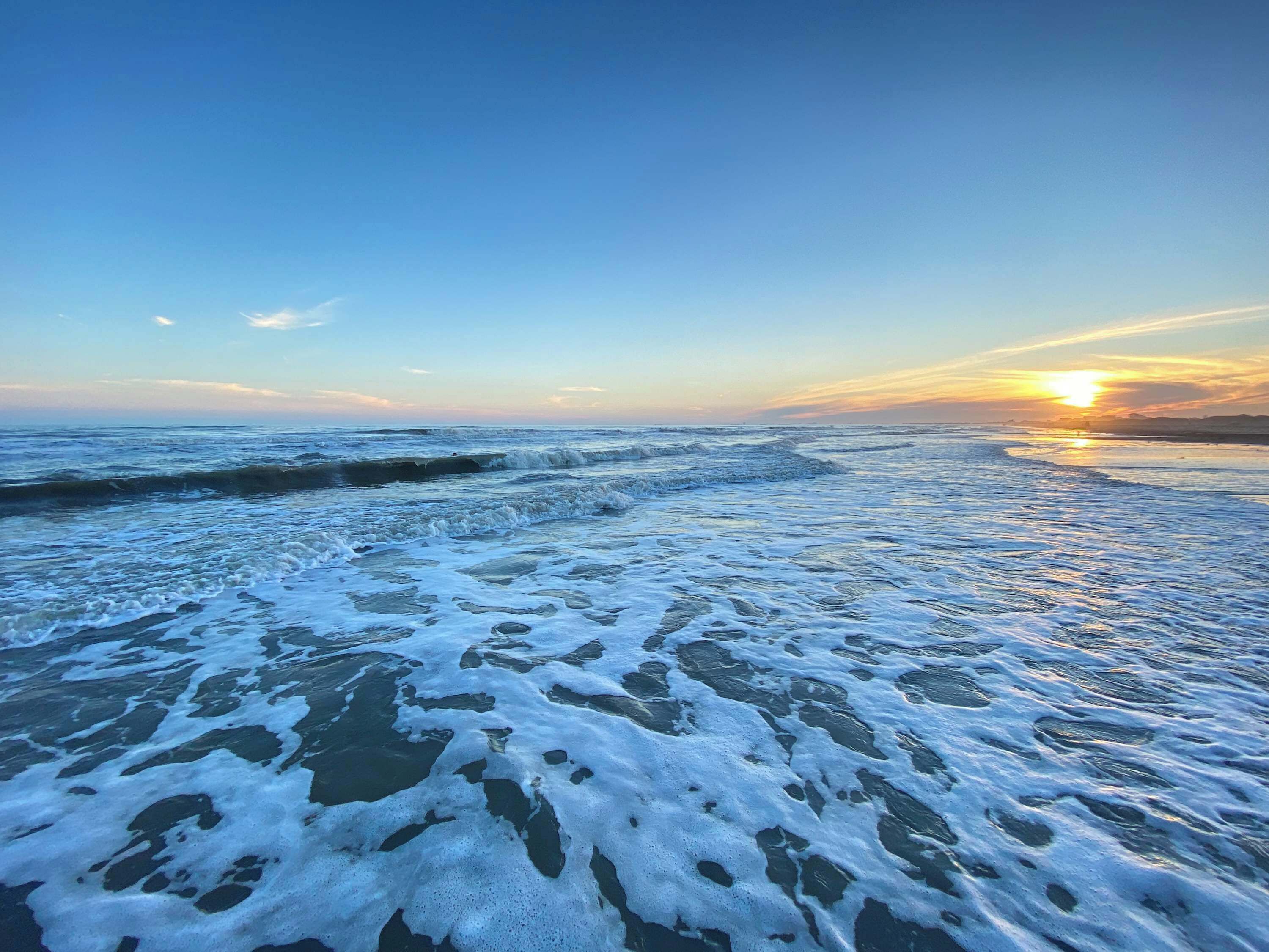 Una spiaggia con onde e un tramonto.