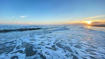 Una spiaggia con onde e un tramonto.