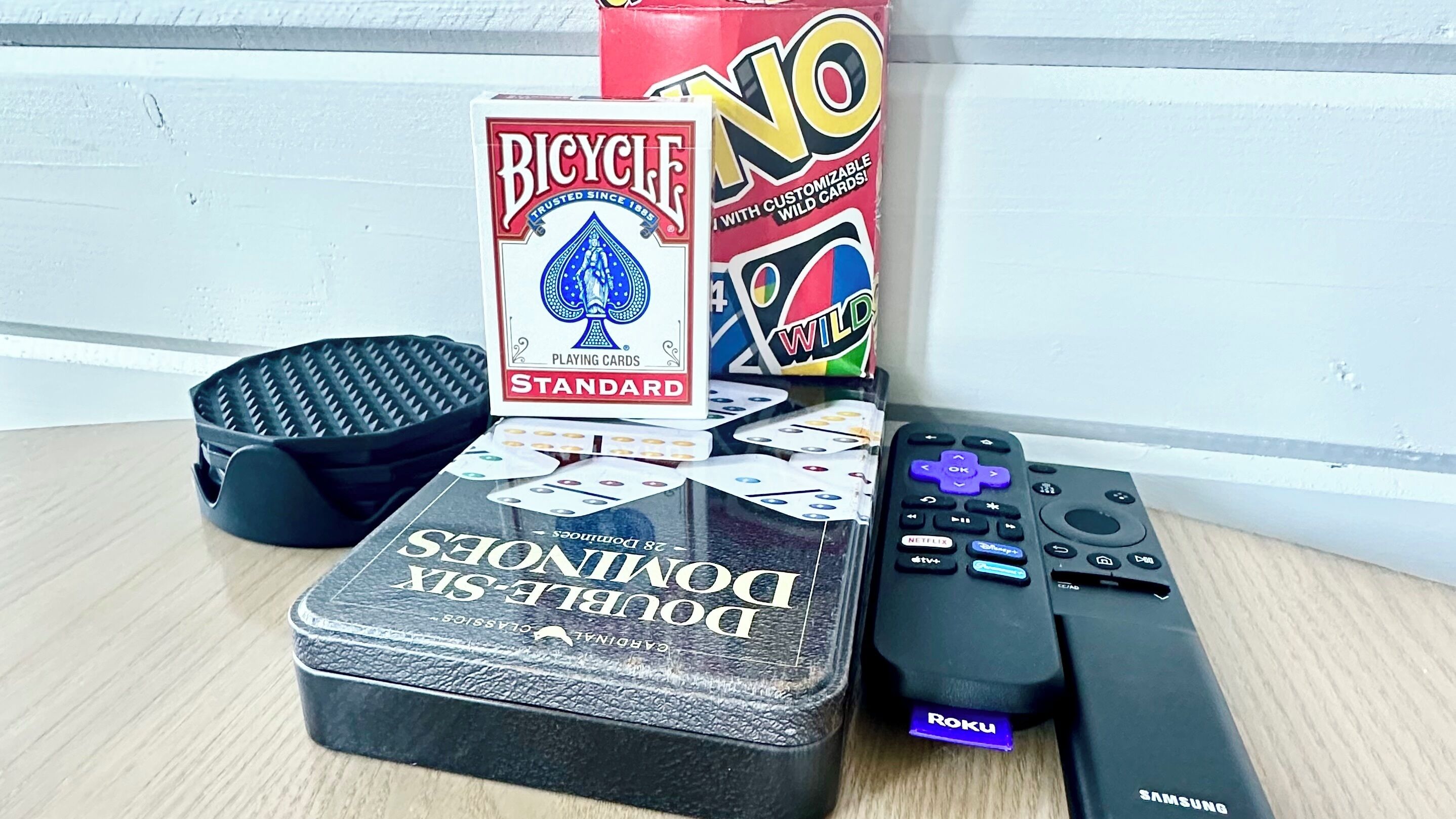 A table with a black tray, a deck of Bicycle Playing Cards, a box of Wild Cards, and a remote control.