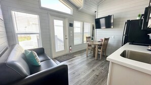 Una cocina moderna con televisión integrada, un comedor con muebles de madera y una zona de estar acogedora con sofá de cuero.