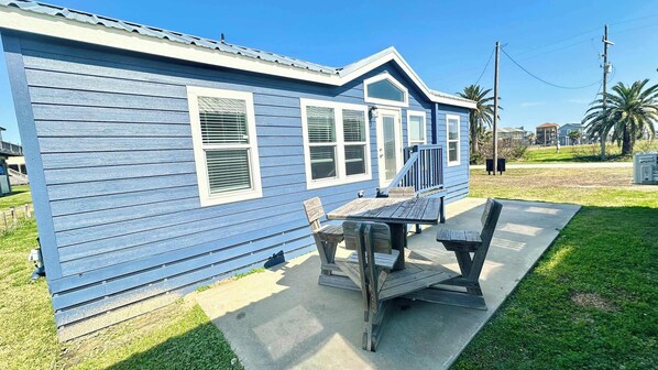 A blue house with a porch, a table, and two chairs.