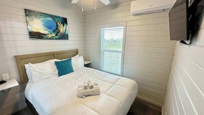 Ein Schlafzimmer mit Bett, Fenster, einem Bild und einer Klimaanlage.