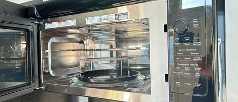A stainless steel oven with a digital control panel listing cooking options like Cook Time, Air Fry, and Sensor Microwave.