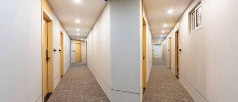 Pasillo de hotel con puertas a ambos lados, alfombra estampada e iluminación empotrada.