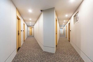 A hotel corridor with doors on both sides, a patterned carpet, and recessed lighting. - Bohu Hotel (Shanghai)