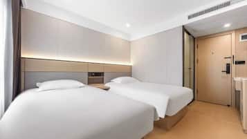 Een hotelkamer met twee bedden, een houten hoofdbord, een nachtkastje en een deur.