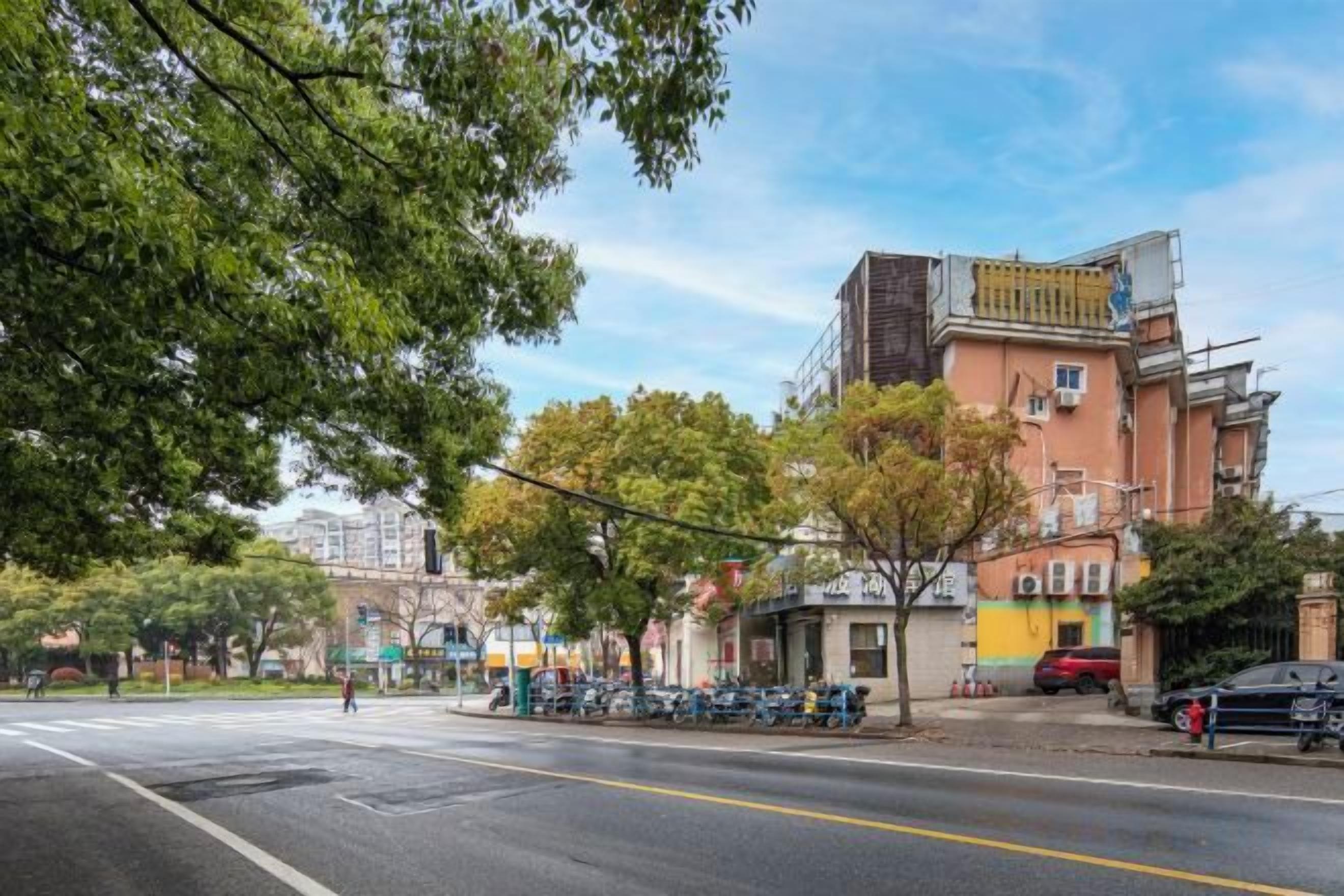 A street view with buildings, trees, and parked cars.