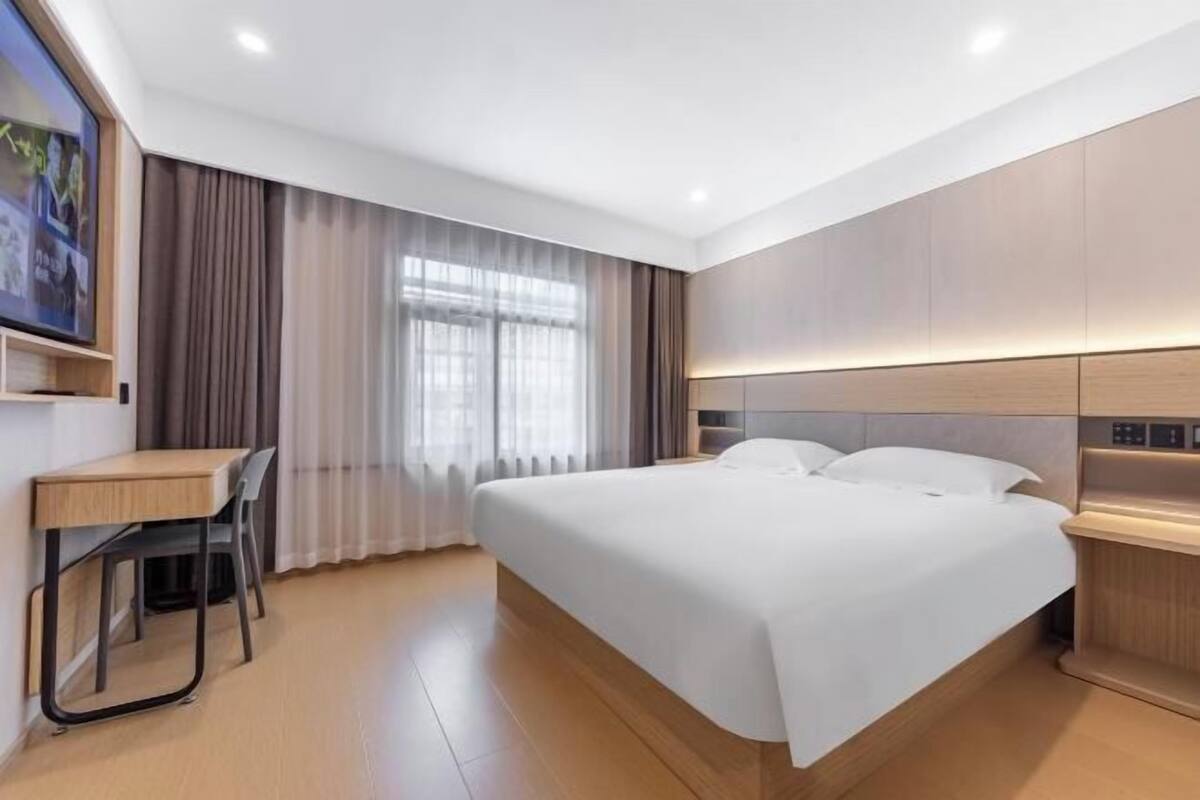 A modern hotel room with a large bed, a desk, and a chair.