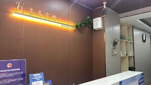 A hotel reception area with a wooden reception desk, a sign with the hotel's name, and informational brochures. - Jiaqi Hotel (Shanghai)