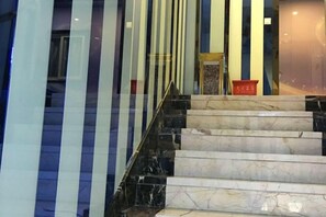 A staircase with marble steps and black railings, leading to a room with a glass wall and a red object on the floor. - Jiaqi Hotel (Shanghai)