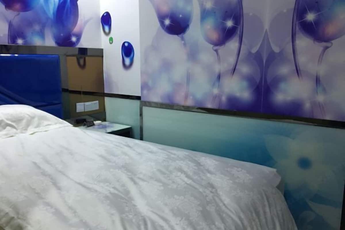 Une chambre d’hôtel avec un lit, un bureau et un mur orné d’un motif abstrait aux couleurs bleu et violet.