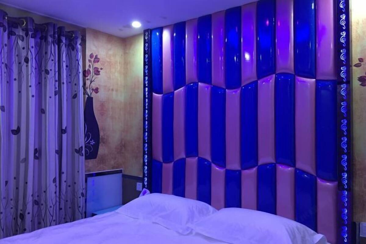Une chambre à coucher avec un lit, un mur décoratif et des rideaux.