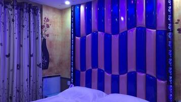 A bedroom with a bed, a decorative wall, and curtains.
