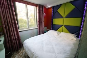 A bedroom with a bed, a window with curtains, a nightstand, and a wall with a geometric pattern.