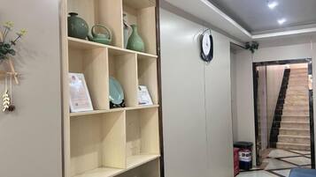 A room with a built-in shelf unit, a clock on the wall, and a tiled floor.