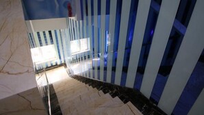 A modern interior with a marble floor, striped blue and white walls, and a staircase leading to a bright area with windows. - Jiaqi Hotel (Shanghai)