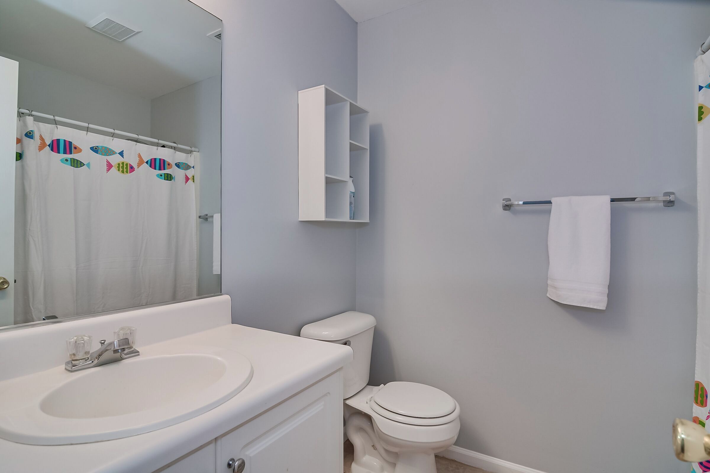 Un bagno con un lavandino bianco, un water, uno specchio e un portasciugamani.