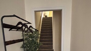 Una escalera con barandilla de madera y un perchero metálico con ganchos.
