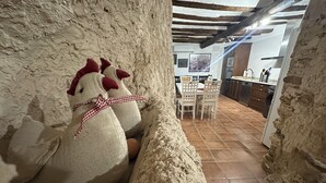 A rustic kitchen with stone walls, a wooden ceiling, and a dining area with a table and chairs. - CASA RURAL LAS MARIPOSAS A HOUSE FULL OF HISTORY TO RELAX IN NAVARRE (Lerín)