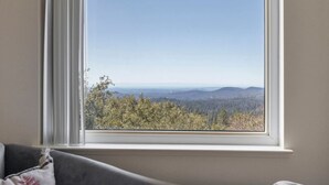 Una habitación con un amplio ventanal con vistas a un paisaje boscoso.