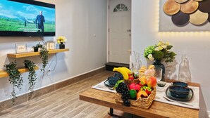 A reception area with a television displaying a landscape scene, a wooden reception desk with a fruit basket, and a wall-mounted art piece. - Ramblei near Chinatown & CenterCity: 1 Bedroom - Unit A (Philadelphia)