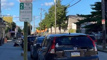 A street scene with parked cars and a sign indicating a no stopping zone.