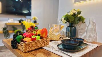 A wooden table with a fruit basket, blue bowls, and a vase with flowers.