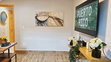 Ett receptionsområde med ett skrivbord i trä, en väggmonterad tv som visar texten ”PUERTO RICO” och ett inramat konstverk.