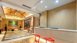 Un área de recepción con piso a cuadros, un mostrador de recepción y dos taburetes rojos.
