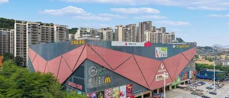 A multi-story building with a distinctive angular roof, surrounded by a parking lot and greenery.