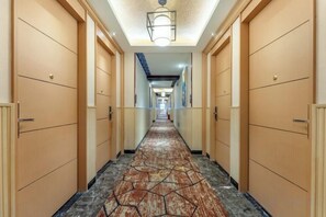 A hotel hallway with a patterned carpet, wooden doors, and a light fixture on the ceiling. - Beihaidao Hotel (Shenzhen Shuangyong Street Metro Station) (Shenzhen)