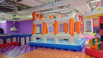 An indoor play area with inflatable structures and a colorful floor.