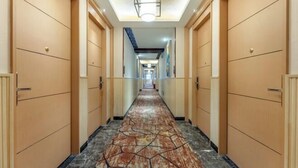 A hotel hallway with wooden doors, a patterned carpet, and a ceiling light fixture. - Beihaidao Hotel (Shenzhen Shuangyong Street Metro Station) (Shenzhen)