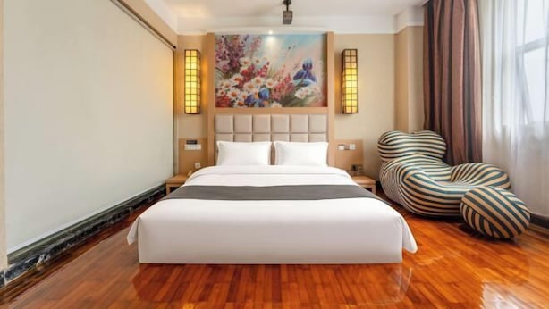 Una habitación de hotel con una cama grande, un cuadro en la pared y una silla a rayas original.