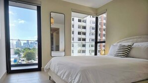 Una camera da letto con un letto grande, uno specchio e vista sulla città attraverso una finestra.