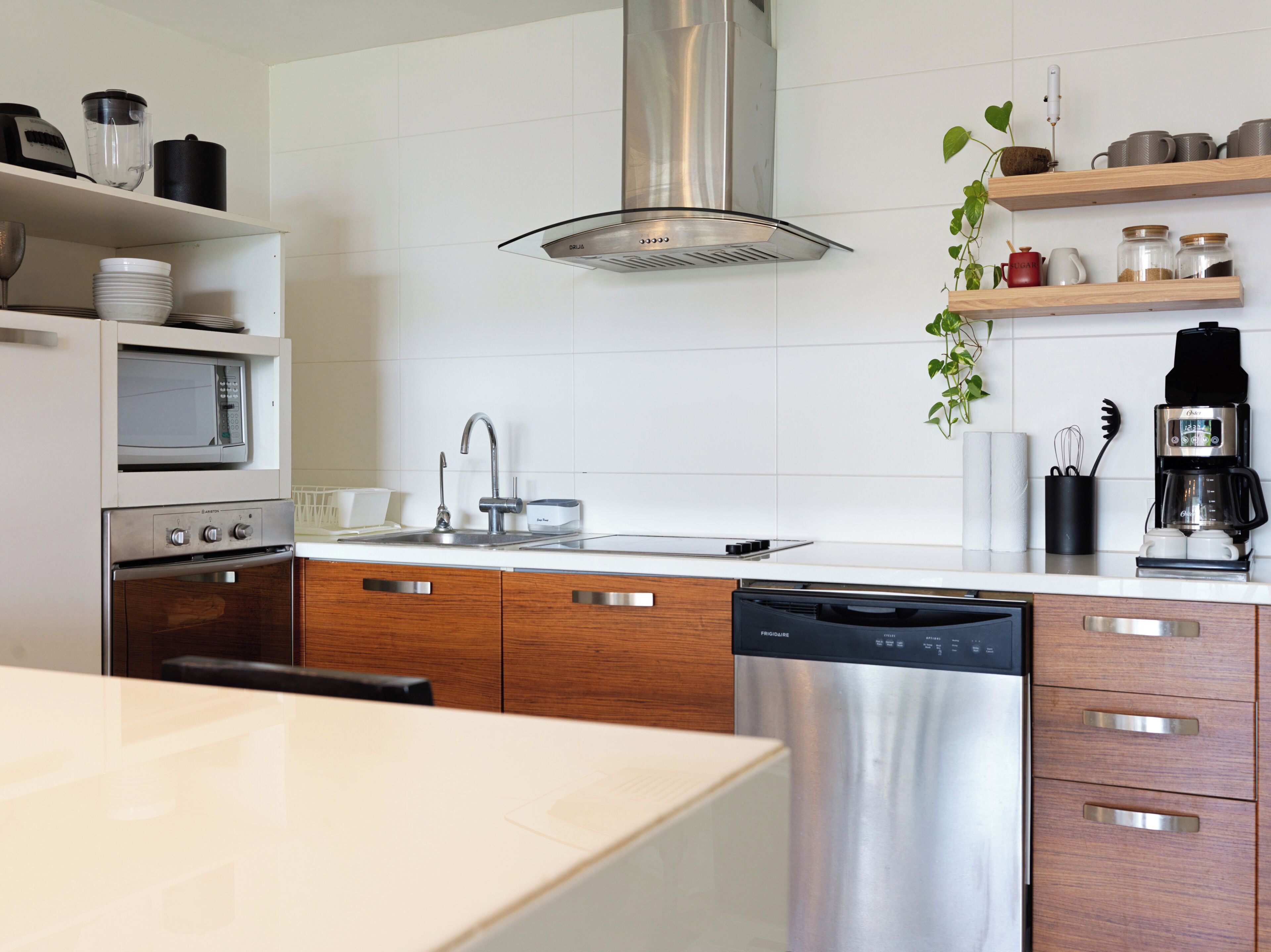 Una cocina moderna con electrodomésticos de acero inoxidable, armarios de madera y salpicadero de azulejos blancos.