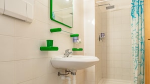 A bathroom with a white sink, green soap dispensers, a mirror, and a shower with a blue curtain. - Villa Bouganville   Il Gelsomino (CAPOLIVERI)