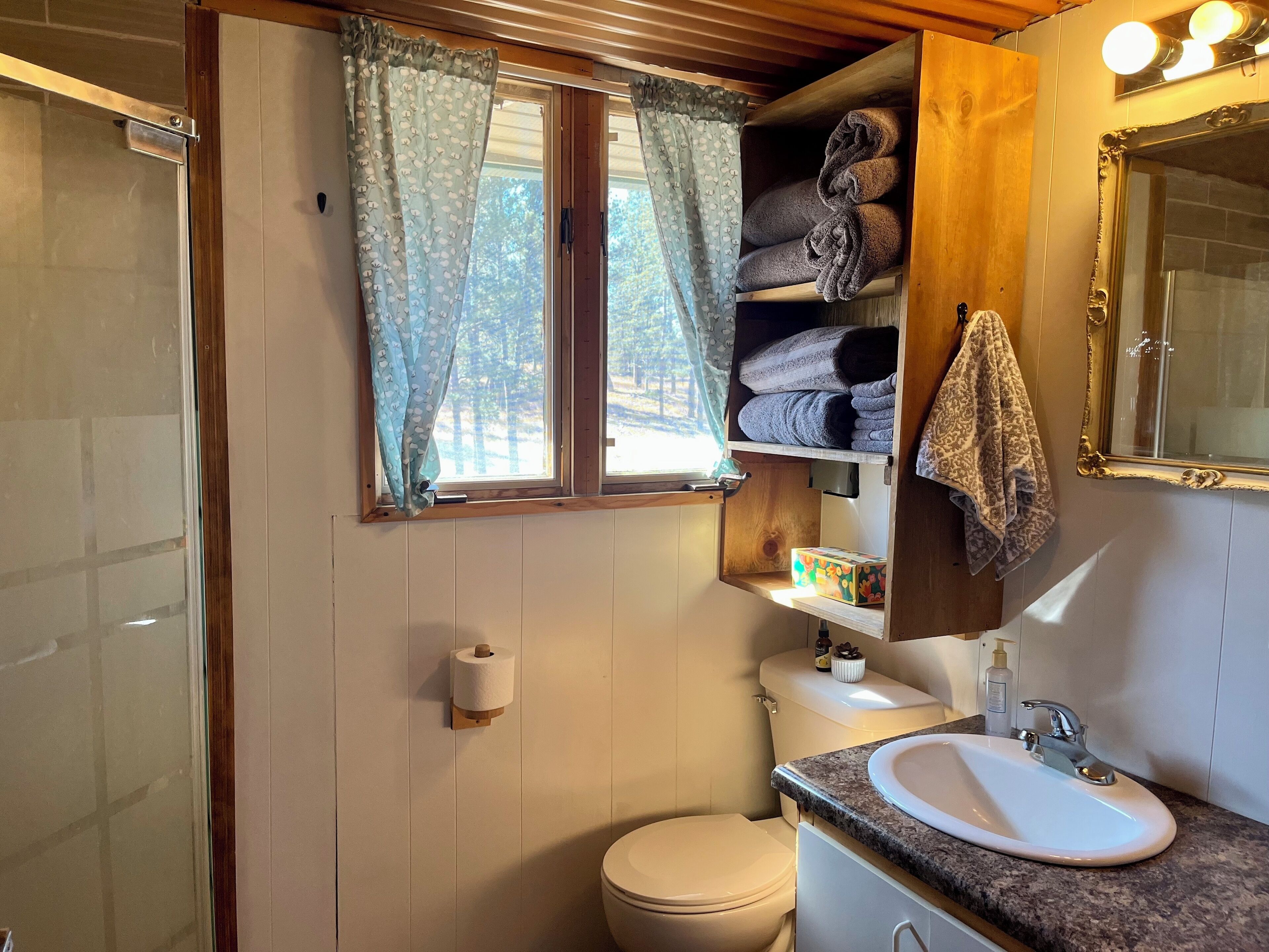 A bathroom with a toilet, sink, and towel storage.