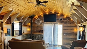 L’intérieur chaleureux d’un chalet avec un plafond en bois, une grande horloge et un coin repas comprenant une table et des chaises.