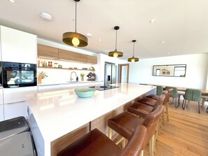 A modern kitchen with a central island, bar stools, and pendant lighting.