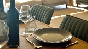 Una tavola imbandita con bicchieri da vino, una bottiglia e un servizio per due persone.