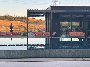 A modern outdoor pool area with seating and a view of a natural landscape.
