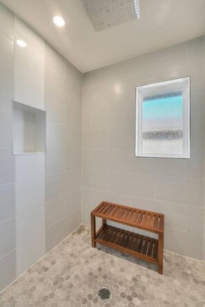 Un espace douche avec un banc, des murs carrelés et un tableau encadré.