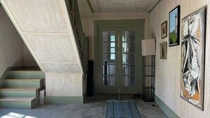 A hallway with a staircase, a door with glass panels, a lamp, and artwork on the wall. - More Boathouse than Lakehouse (Newcastle)