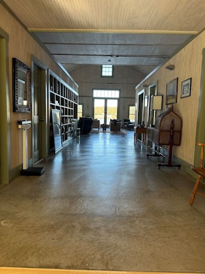 A spacious hallway with a high ceiling, large windows, and a central seating area.