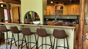 A rustic kitchen with wooden cabinets, a bar area with stools, and a patterned rug. - Rose Mountain Lodge - Friday Harbor (Friday Harbor)