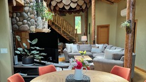 A cozy living room with a round wooden table, orange chairs, a fireplace, and a stone wall. - Rose Mountain Lodge - Friday Harbor (Friday Harbor)